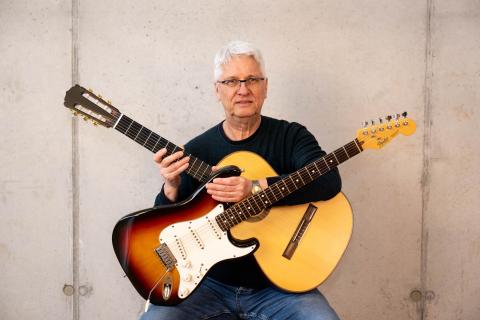 Das Bild zeigt den Fachbereichsleiter für Zupfinstrumente, Rock|Pop und Inklusiven Unterricht Bernhard Fuchs mit zwei Gitarren.