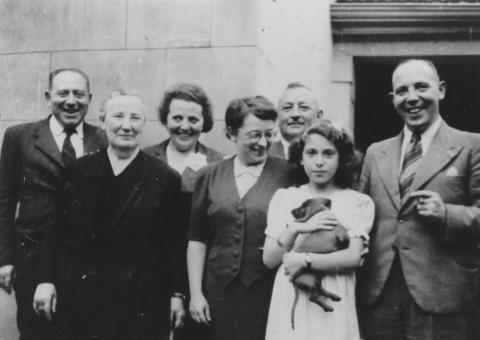Lina Kann mit ihrer Familie in Buenos Aires Schwarz-Weiß-Foto von sieben Personen, die nebeneinander stehen und in die Kamera lächeln. Ein Mädchen im Teenageralter hält einen Hund auf dem Arm.