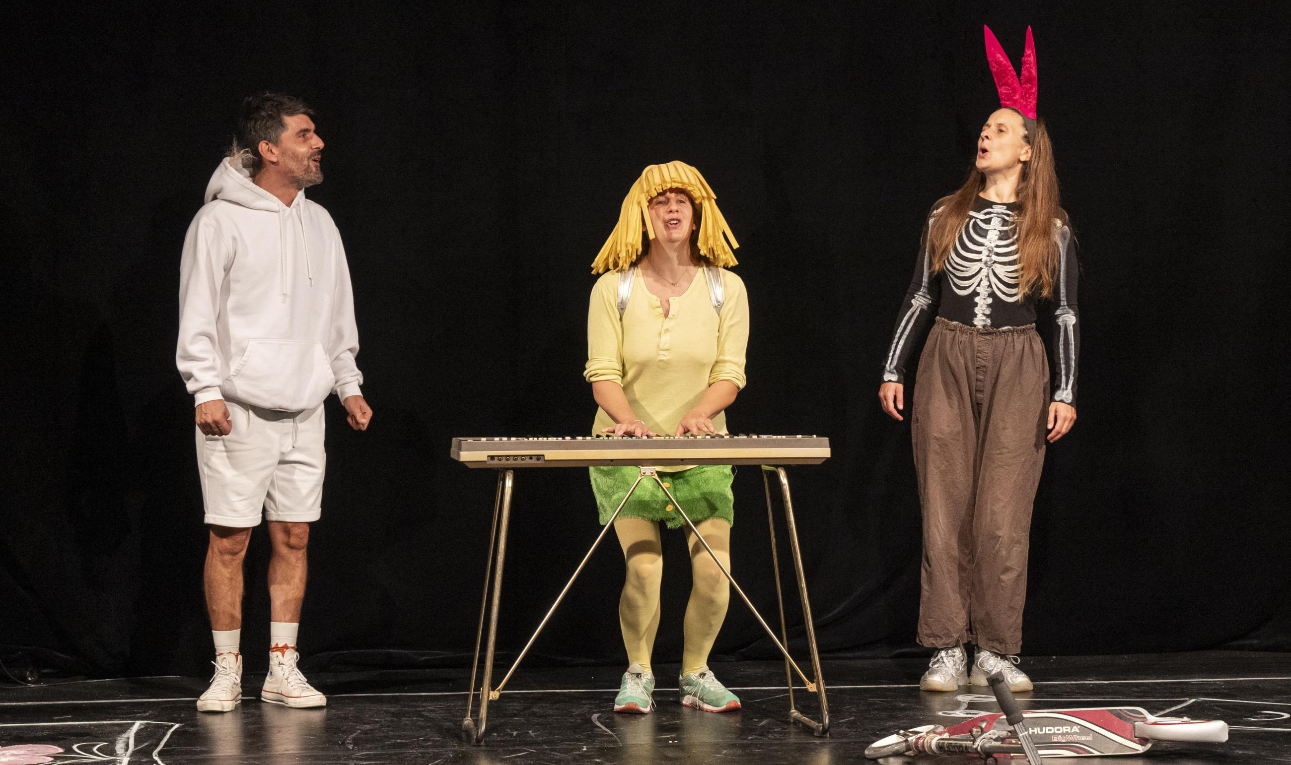 Es stehen drei Schauspieler*innen auf einer Bühne und zeigen das Stück DIE BESTIMMER, entwickelt von Bekim Aliji, Gesine Hohmann und Elisa Kühnl vom Theater an der Ruhr, frei nach dem Bilderbuch von Lisen Adbåge.