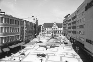 <p><span>Blick auf die „Alte Post“ mit dem damals neugestalteten Viktoriaplatz, heute Synagogenplatz, durch den Bildhauer Otto Herbert Hajek, 1977, Fotografie, Medienkompetenzzentrum</span></p>