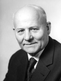 Porträt von Heinrich Thöne. Er hat eine Glatze und trägt einen Anzug mit Krawatte.