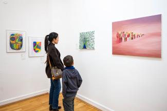 Eine Ausstellungssituation im Kunstmuseum. Eine Frau steht mit ihrem Sohne in einer Ecke eines Raumes und betrachtet ein Kunstwerk.