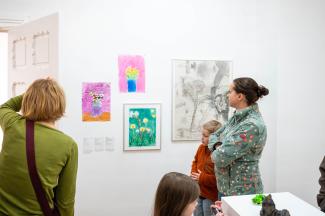 Ausstellungssituation. Personen stehen vor Kunstwerken.