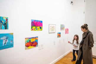 Ausstellungssituation, Mutter mit Tochter schauen sich Kunstwerke an.