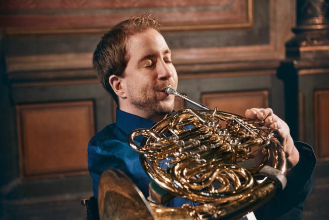 Das Bild zeigt den Hornisten Felix Klieser mit einem Horn. Er tritt am 6. Dezember 2024 als Solist in der Stadthalle bei den Sinfoniekonzerten auf.