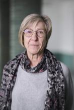 Das Bild zeigt ein Porträtfoto von Monika Behrns, Mitarbeiterin im Kunstmuseums Mülheim an der Ruhr. Das Foto wurde im Museumsfoyer aufgenommen. Im Hintergrund sind die charakteristischen grün gekachelten Säulen erkennbar.