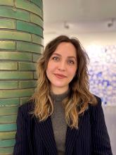 Eine lachende Frau steht an einer grünen Säule.